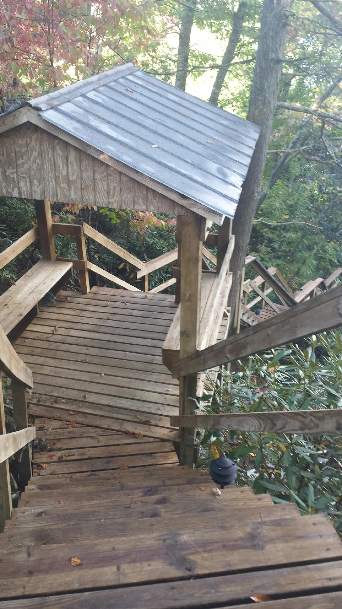Metal roofed shelter over wooden steps on a wooded walkway — Skylight Repair & Installation work by our crew in Fall River