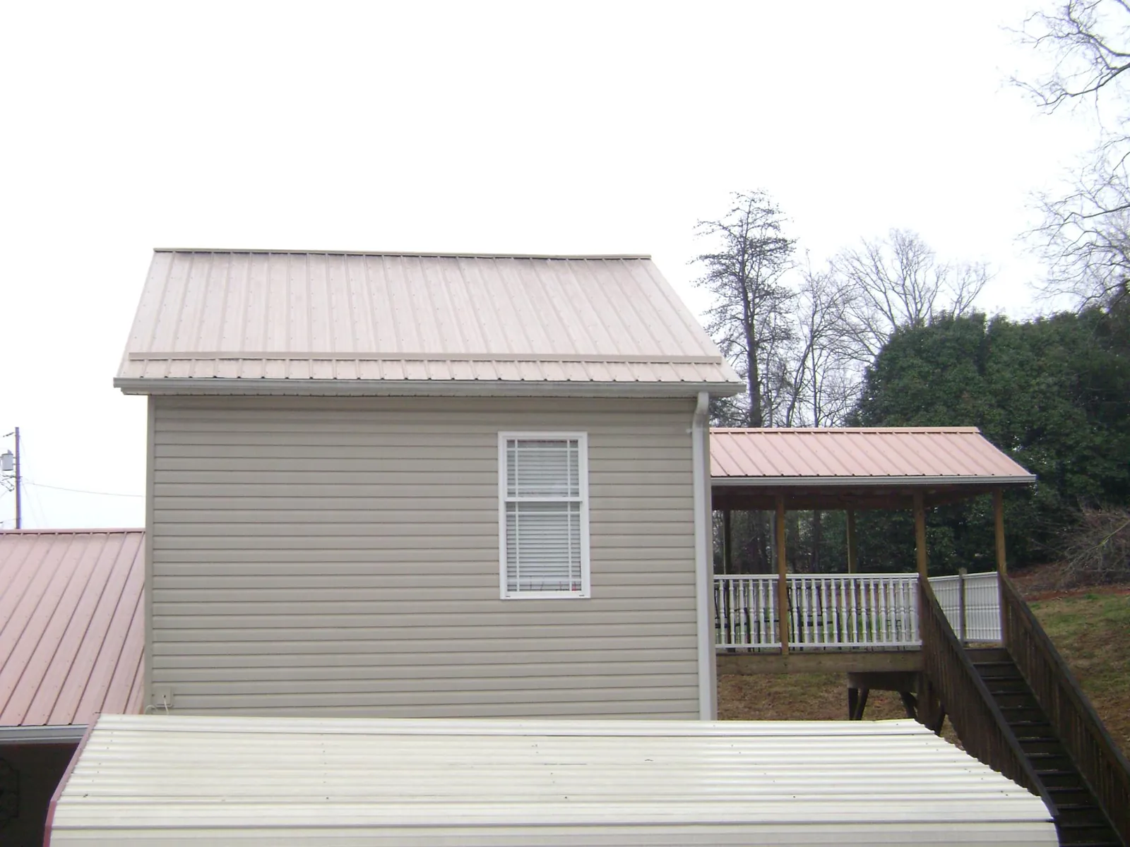 Tan metal roofs on a two story addition and attached porch, from a Roof Replacement job in Fall River